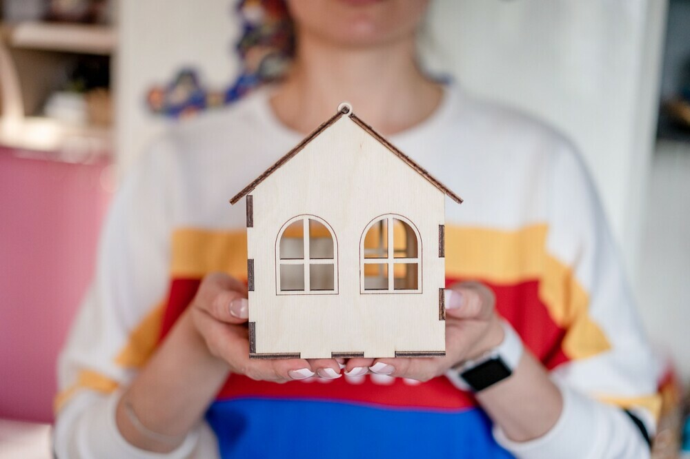 Image of a woman showing the picture of her new home happily on the banner of RETIREMENT SUCCESS TALK stressing on homeownership culture, Real Estate Business