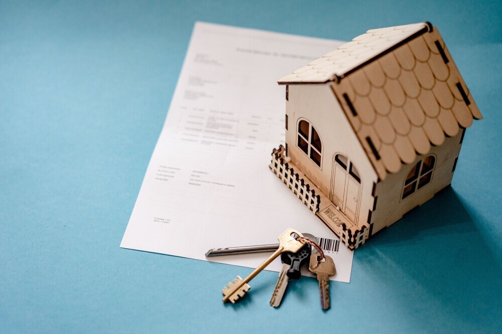 image of a model house with a pair of keys and a homeownership certificate.